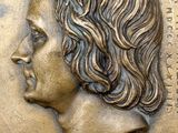 bronze plaque of a woman ' s profile with a quote on it