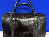 un sac en cuir noir posé sur une table blanche