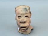 une sculpture en argile représentant le visage d'un homme sur une surface grise