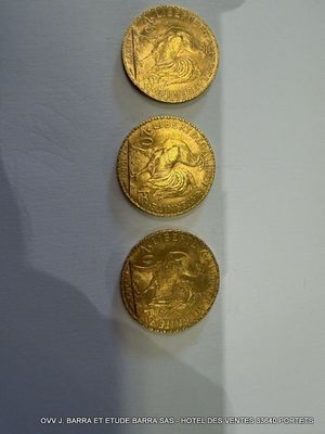 trois pièces d'or posées sur une table près d'un mur blanc