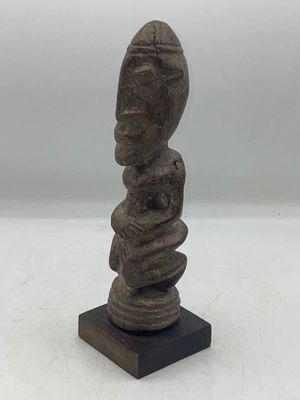 un gros plan d'une statue posée sur un socle en bois, sur une surface blanche