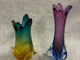pair of colorful glass vases sitting next to each other on a gray surface
