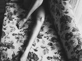 black and white photograph of a naked woman sitting on a floral couch