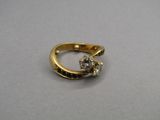 une bague en or sertie d'un diamant, posée sur une table