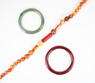 un collier de perles et une paire de bracelets posés sur une surface blanche