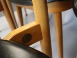 a close up of a wooden chair with a black seat