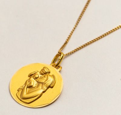 un gros plan sur un collier en or orné d'un bébé