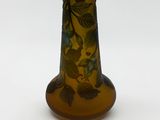 a brown vase with green leaves on it on a white surface