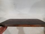 someone is holding a piece of wood that is sitting on top of a table