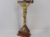 crucifix en or posé sur un socle en bois, sur fond blanc