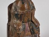une vieille statue en bois représentant un homme assis sur une chaise