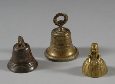 three brass bells sitting next to each other on a white surface