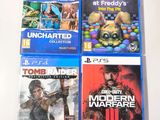 four playstation game covers on a white table with a white background