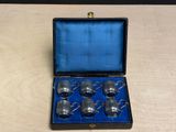 six silver cups in a case on a table