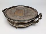 une assiette en argent ornée d'un oiseau sur un fond blanc
