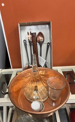 une assiette en cuivre sur laquelle sont posées des cuillères et des ustensiles
