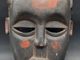 a black mask with red spots on the face