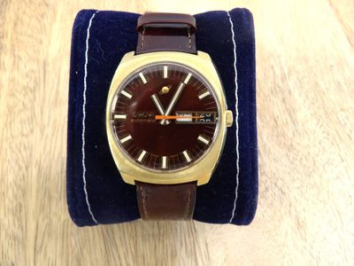 une photo d'une montre-bracelet avec un bracelet en cuir marron posée sur une table en bois