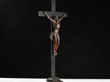 a bronze statue of jesus on the cross with a black background