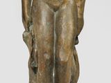 bronze statue of a man sitting on a rock with his hands in his pockets