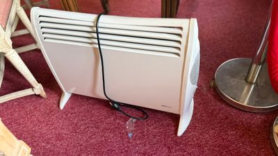 un radiateur blanc posé par terre à côté d'une chaise rouge