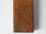 an old book sitting on top of a white table next to a white wall