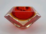 un vase en verre rouge posé sur une surface blanche