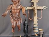 a statue of a child holding a cross next to a candle