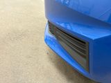 the front end of a blue car with a shiny bumper