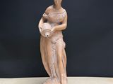 statue of a woman holding a vase on a table