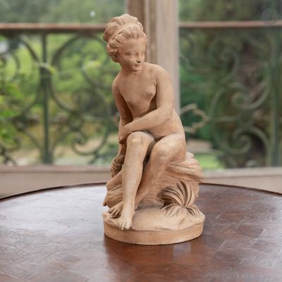 une statue représentant un garçon assis sur une table en bois