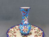 un vase bleu et rouge posé sur une assiette, sur une table