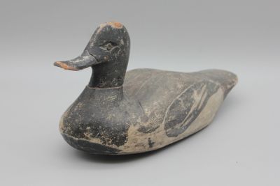 un vieux canard en bois posé sur une surface blanche