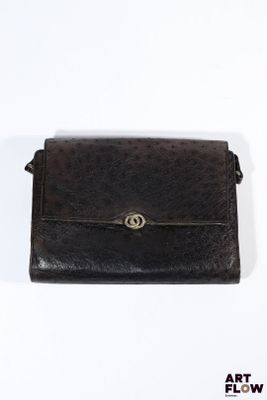 une photo d'un sac à main noir posé sur une surface blanche