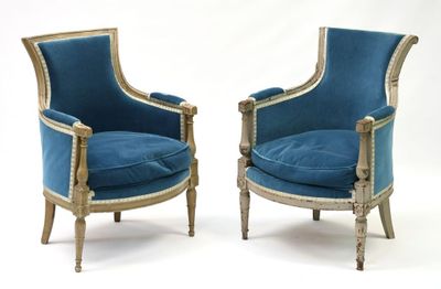 une paire de fauteuils en velours bleu, avec des bordures dorées et des pieds en bois
