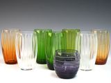 plusieurs vases en verre de différentes couleurs sont alignés sur une surface blanche
