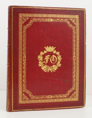 un vieux livre rouge aux tranches dorées, avec un monogramme doré sur la couverture