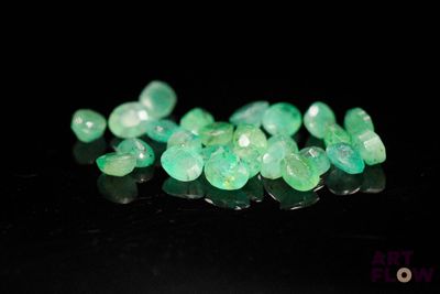 a close up of a bunch of green gems on a black surface