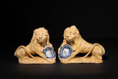 pair of lion figurines with blue and white plates on black background