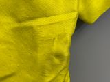 the back view of a yellow shirt with a small patch on the chest