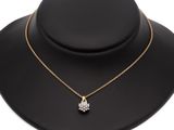 a gold necklace with a flower pendant on a mannequin neck
