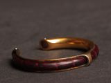 a close up of a red and gold bracelet on a black surface