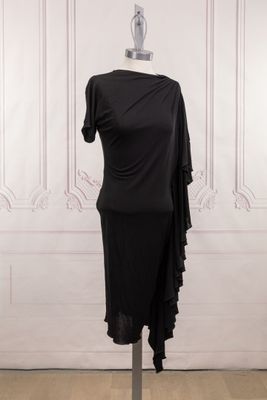 une robe noire posée sur un mannequin devant un mur blanc