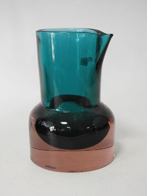 a blue glass vase with a brown base on a white surface