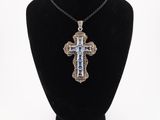 a silver cross pendant on a black mannequin necklace