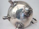 a silver pig shaped teapot on a white table