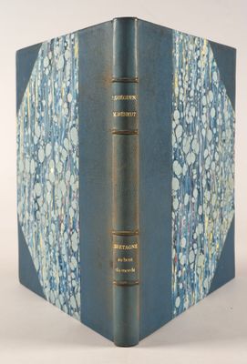 un vieux livre à la couverture bleue posé sur une table blanche