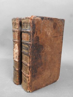 two old books sitting on top of each other on a table