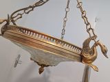a large brass hanging light fixture with a bird on it