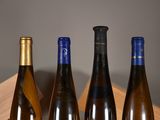 three bottles of wine are lined up on a wooden shelf